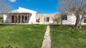 Una casa moderna con un camino empedrado que conduce a la entrada, rodeada de un césped cuidado y algunos árboles.