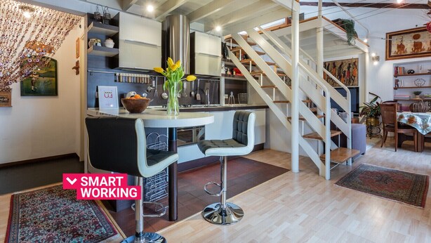 Une cuisine moderne dotée d’un îlot central, d’un coin repas avec une table et des chaises, et d’un escalier menant à un niveau supérieur.