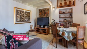 Un salon comprenant un canapé, une table à manger, des chaises, un téléviseur et des œuvres d’art accrochées aux murs.