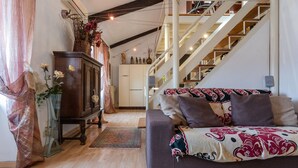 Un salon chaleureux avec un canapé, un meuble en bois et un escalier.