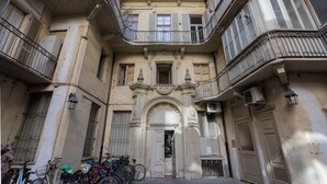 A multi-story building with a central entrance, balconies, and bicycles parked outside.
