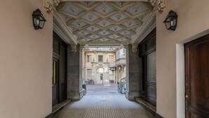 A corridor with ornate ceiling and large doors leading to a building with balconies. - La Maison du Vent by Wonderful Italy (Torino)