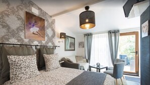Ein Schlafzimmer mit einem großen Bett, einem Schreibtisch, einem Stuhl und einem Balkon mit Vorhängen.