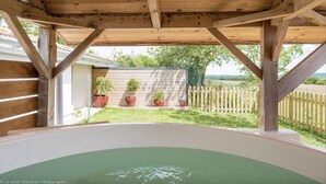 Eine Pergola aus Holz mit einem Whirlpool darunter.