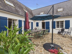 A courtyard with a stone floor, outdoor seating, and blue shutters.