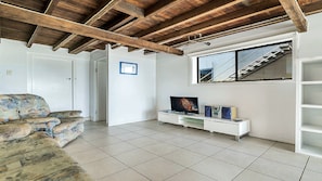 A living room with a sofa, a TV, and a white entertainment unit. - Minnie Water Beach House (Minnie Water)