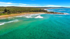 Eine Küstenlandschaft mit klarem türkisblauem Wasser, einem Sandstrand und einem bewaldeten Gebiet.