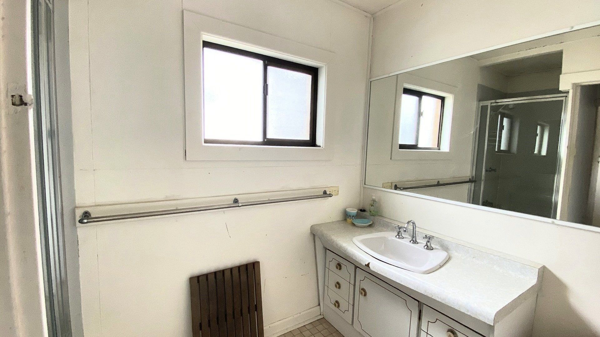 A bathroom with a window, a sink, a mirror, and a radiator.