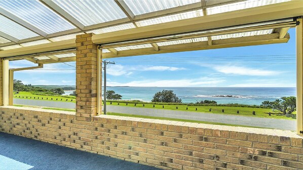 A covered outdoor area with a view of the ocean and a road. - Minnie Water Beach House (Minnie Water)
