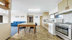 A compact kitchen with a dining table, chairs, a stove, and a microwave.