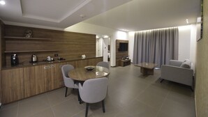 A modern living room with a sofa, a TV, and a dining area with a table and chairs. - ZETT HOTEL (Jounieh)