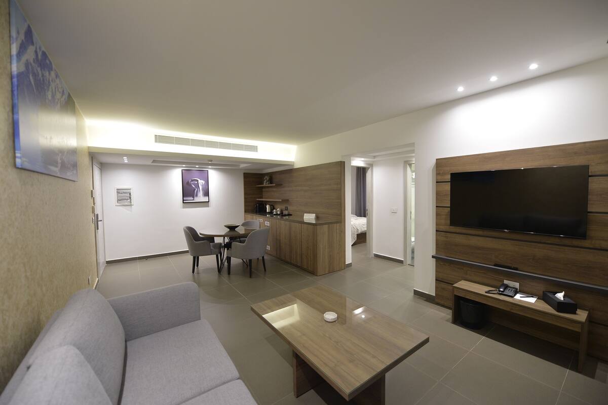 Una sala moderna con un sofá, una mesa de centro, un televisor y un área de cocina con comedor.