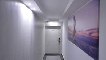 A hallway with a door at the end, a patterned floor, and a large wall-mounted artwork.