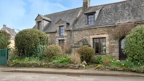 A stone house with a sloped roof, multiple windows, and a stone wall surrounding the property. - Sarzeau – Stunning house for 10, garden & BBQ (Sarzeau)