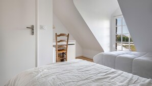 A bedroom with a sloped ceiling, a wooden chair, and a bed with white bedding. - Sarzeau – Stunning house for 10, garden & BBQ (Sarzeau)