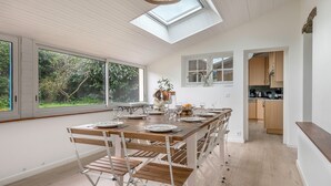 A modern kitchen with a skylight, wooden dining table, and chairs. - Sarzeau – Stunning house for 10, garden & BBQ (Sarzeau)