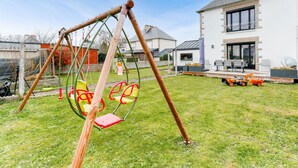 A swing set in a grassy yard with a house in the background. - 1km Prieuré Beach - Dinard- House for 6 (Dinard)