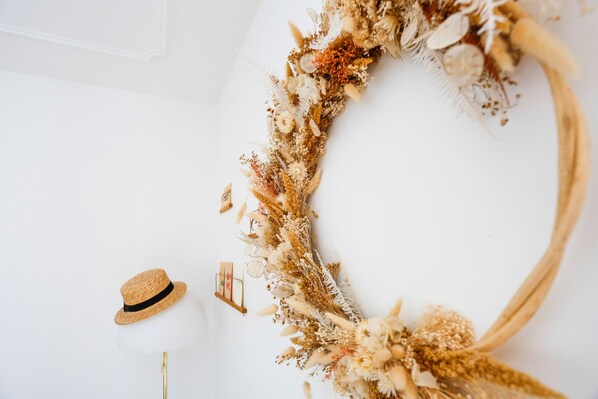 A white wall with a decorative wreath and a straw hat.