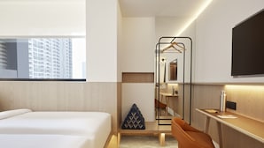 Une chambre d’hôtel moderne équipée d’un lit, d’un bureau, d’une chaise et d’un porte-vêtements.