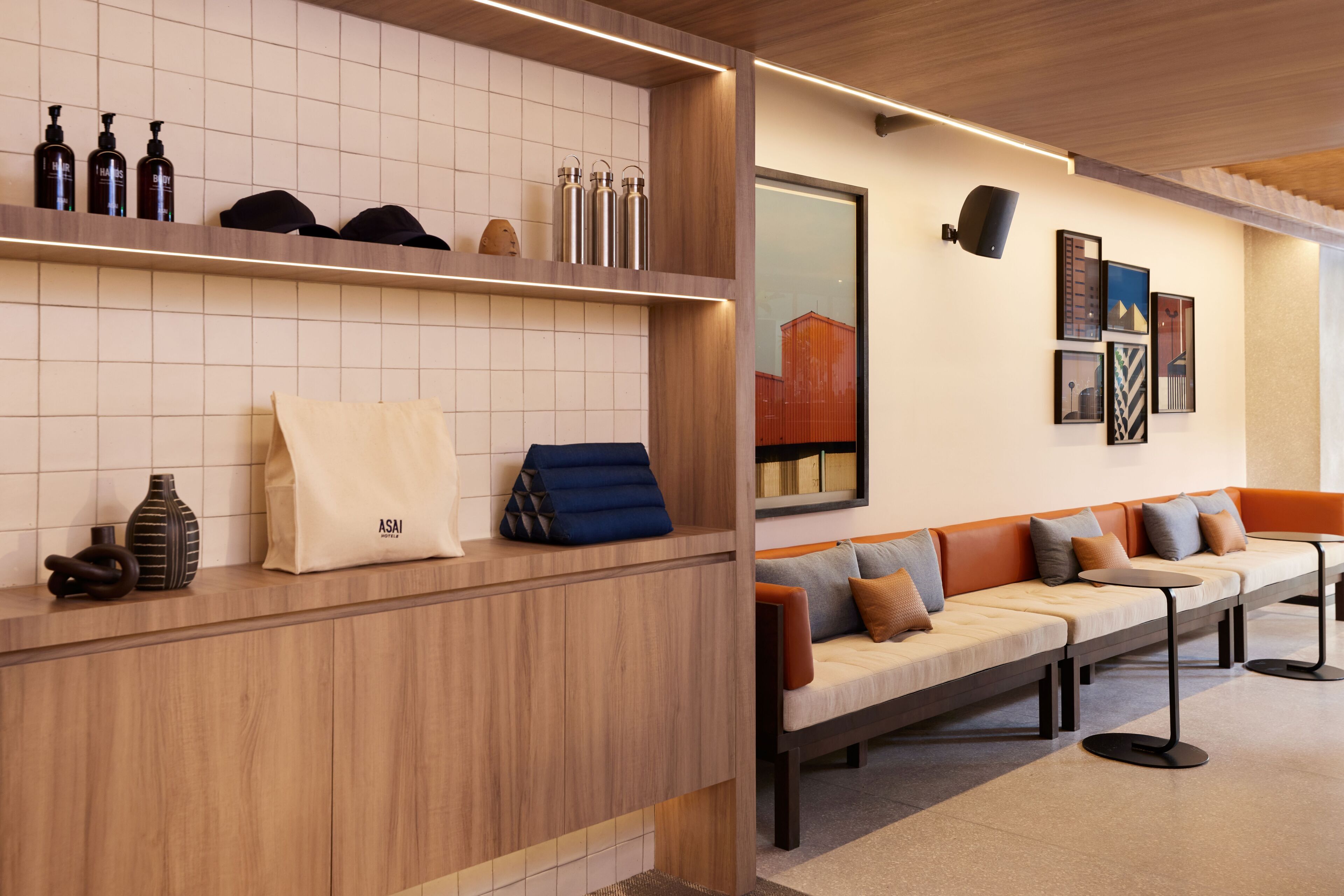 Una zona de recepción con un mostrador de madera, un sofá con cojines y una pared decorada con cuadros.