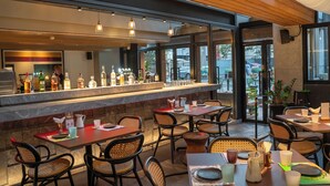 Un restaurant doté d’un bar, de chaises en osier et offrant une vue sur l’extérieur.