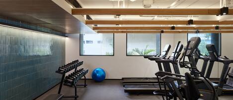 Een sportschool met loopbanden, elliptische trainers en losse gewichten.