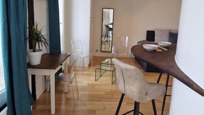 A modern living space with a wooden floor, a dining area with a table and chairs, a kitchen area with a countertop and appliances, and a large mirror on the wall. - Innocenti, brand new studio, heart of Paris (París)