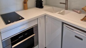 A modern kitchen with white cabinets, a built-in oven, a dishwasher, and a coffee maker on the countertop. - Innocenti, brand new studio, heart of Paris (París)
