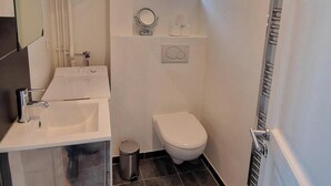 A compact bathroom with a sink, toilet, and a small window. - Innocenti, brand new studio, heart of Paris (París)