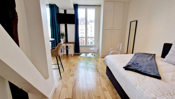 A bedroom with a bed, a desk, and a chair. There is a window with curtains, and a balcony with a railing. - Innocenti, brand new studio, heart of Paris (París)
