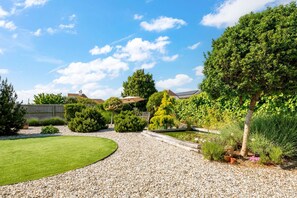 A well-maintained garden with a variety of plants and a gravel path.