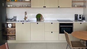 A modern kitchen with light-colored cabinets, a central island, and a dining area with wicker chairs. - 27. 2-bedroom apt with balcony, private roof terrace, parking and pool (Vallauris)