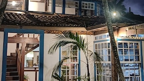 Un edificio de dos pisos con techo de tejas y ventanas con marco azul.