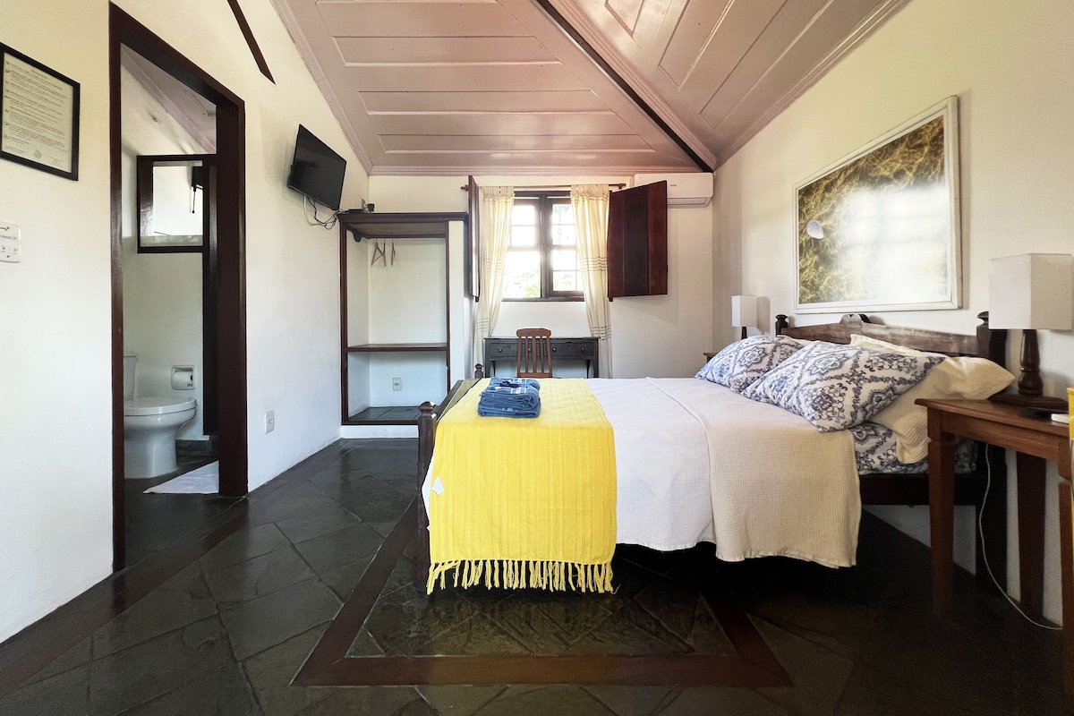 Un dormitorio con cama, escritorio, silla, televisor y ventana con cortinas.