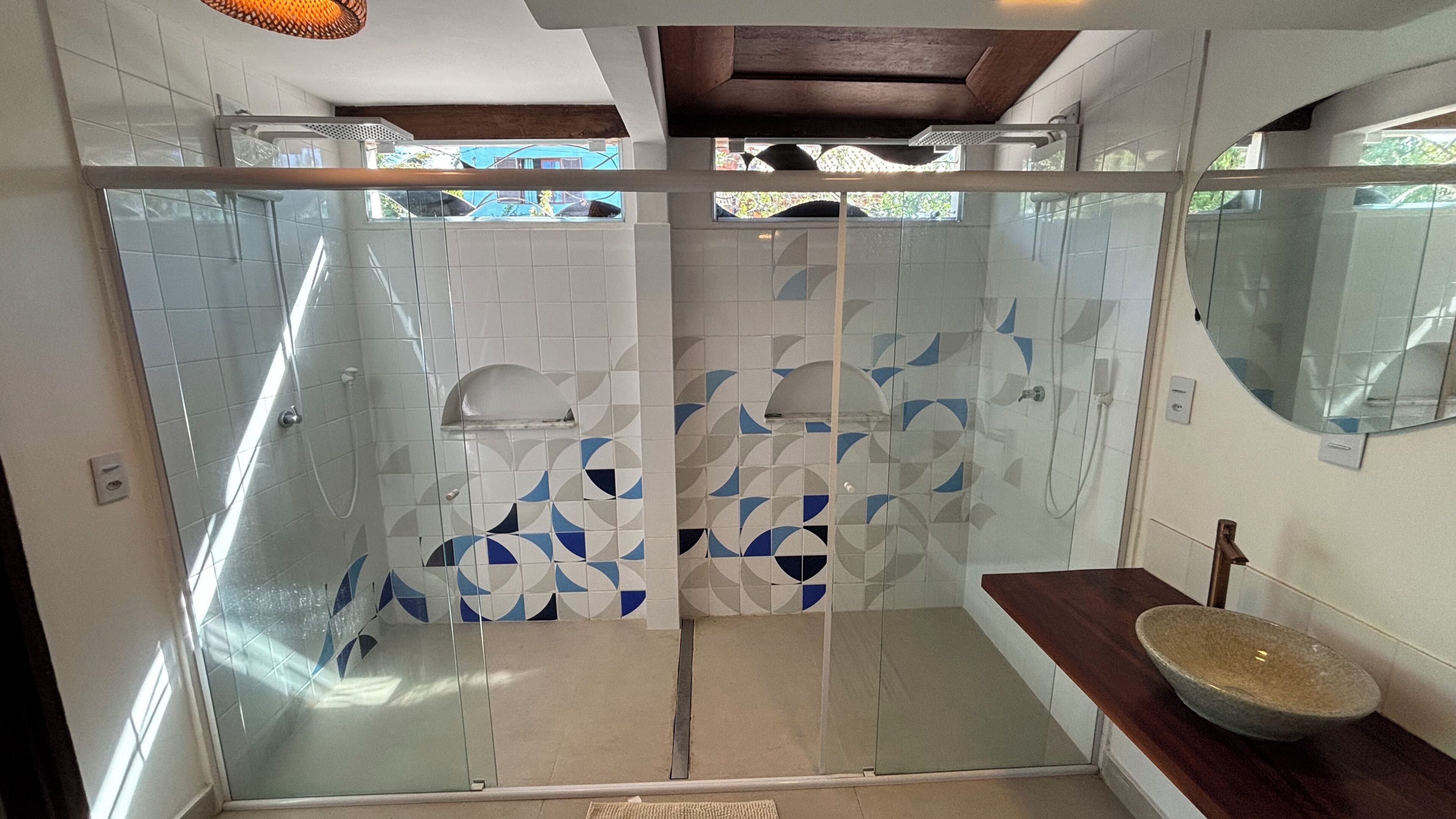 A modern bathroom with a glass shower enclosure, a wooden vanity, and a large mirror.