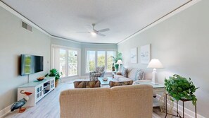 A living room with a sofa, TV, and a ceiling fan.