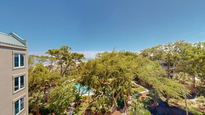 Zona residencial con piscina rodeada de árboles y un edificio con varias ventanas.