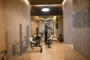 Ein Fitnessraum mit Trainingsgeräten, einem Spiegel und einer Deckenleuchte.