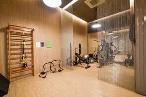 Un gimnasio con equipo de ejercicios, un estante de madera y un espejo.