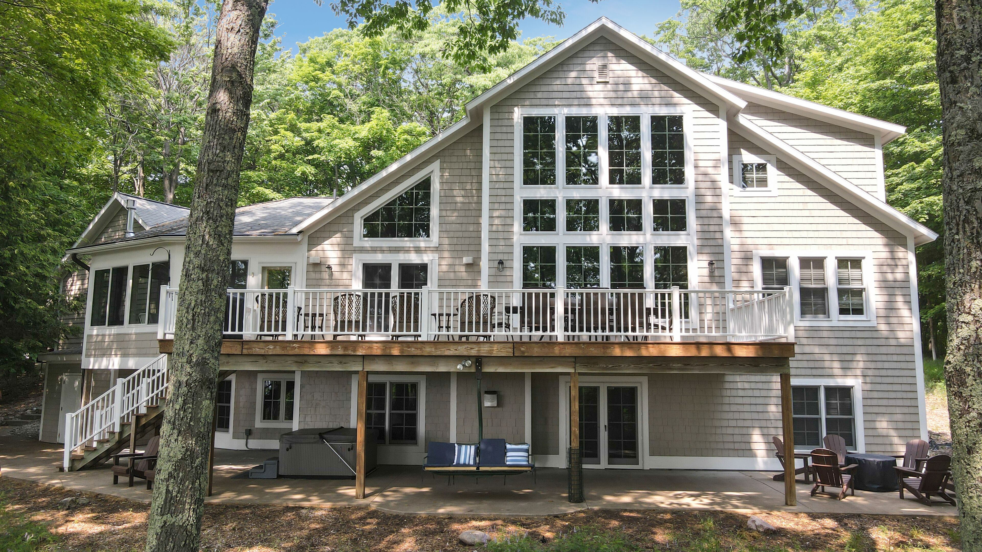 A two-story house with a balcony, large windows, and a covered porch area.