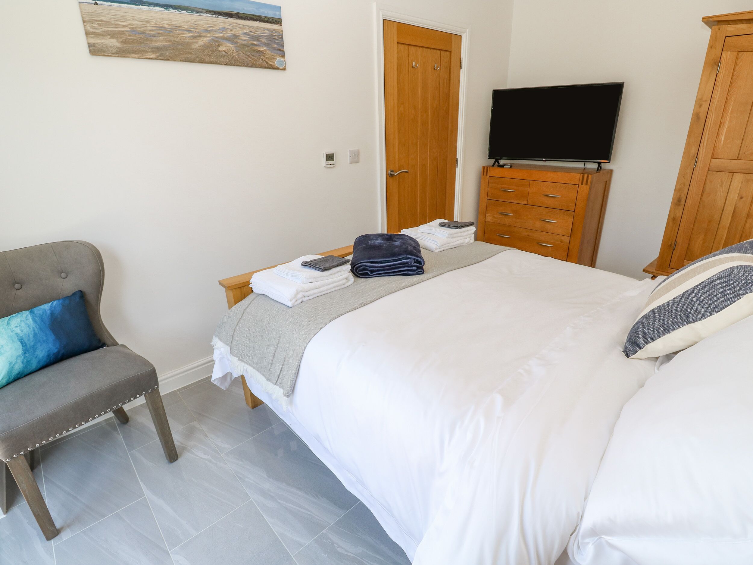 Une chambre à coucher avec un lit, une chaise, un téléviseur et une armoire en bois.