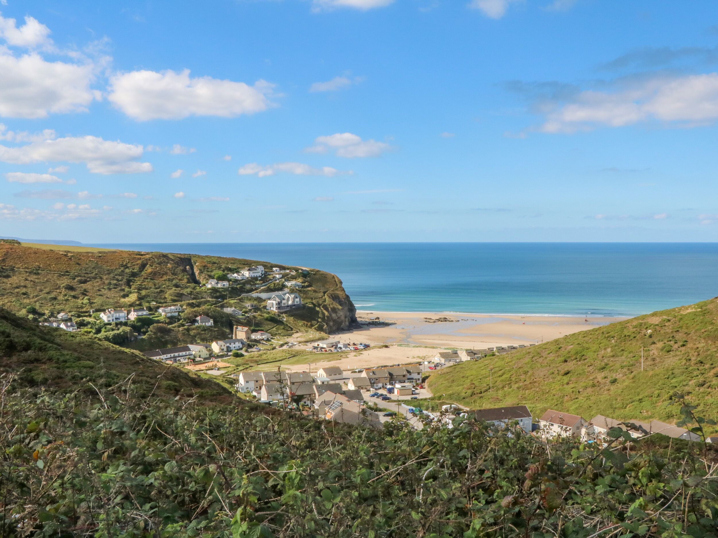 A coastal village with houses on a hillside overlooking a beach.