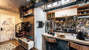 A modern kitchen with a built-in island, wooden shelves, and a variety of appliances. - Praca Benedito Calixto - Duplex (São Paulo)