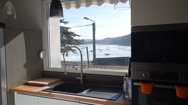 A kitchen with a window view of a harbor, a sink, and a stove. - Waterfront villa with panoramic sea view (Logonna-Daoulas)