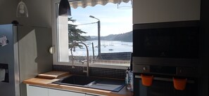 A kitchen with a window view of a harbor, a sink, and a stove. - Waterfront villa with panoramic sea view (Logonna-Daoulas)