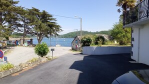 A coastal road with a white building, a no parking sign, and a view of boats on the water. - Waterfront villa with panoramic sea view (Logonna-Daoulas)