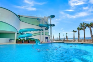 A pool area with a water slide and palm trees.