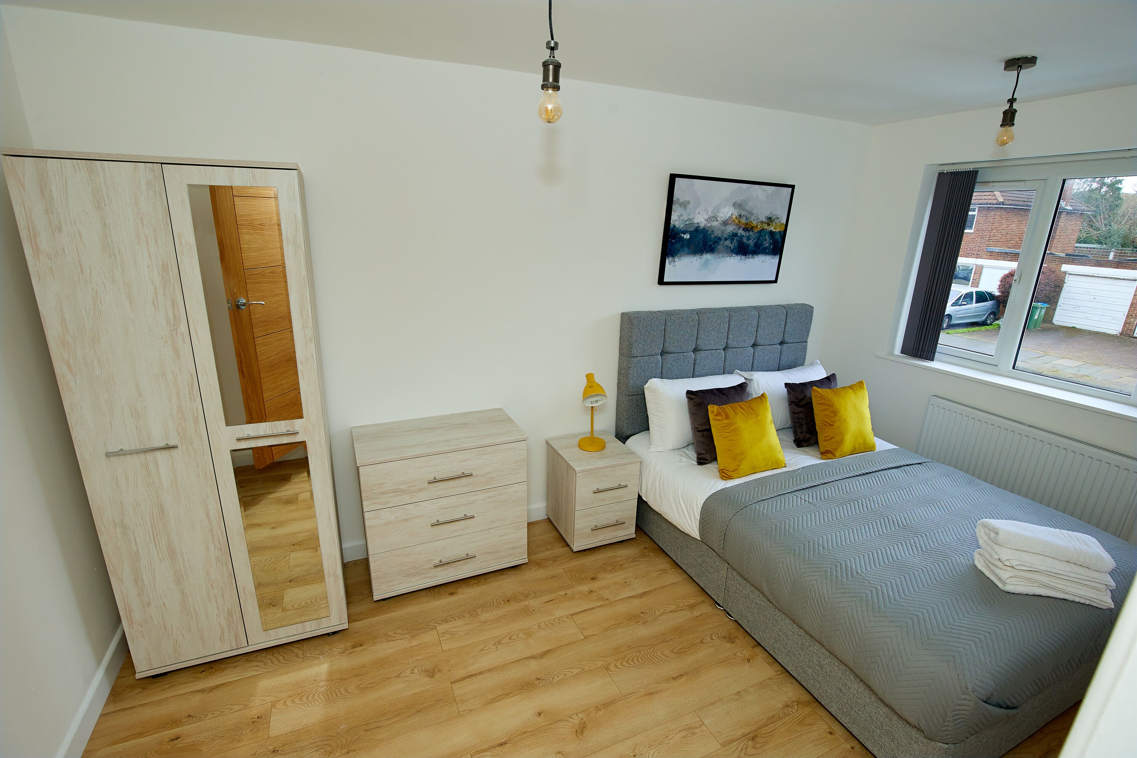 Un dormitorio con cama, mesita de noche, lámpara y armario.