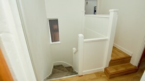 Een trap met houten treden en witte leuningen, die naar een verdieping leidt.