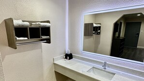 A bathroom with a white sink, a large mirror, a towel rack, and a wooden floor. - Hollywood Inn (Houston)